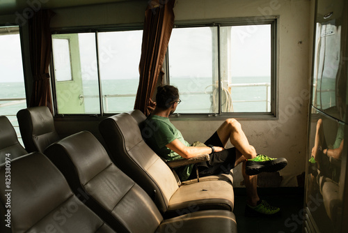 Young man sitting on a ferry boat. photo