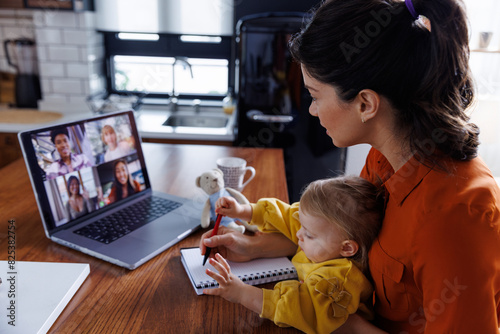 Working mother with daughter during video conference photo