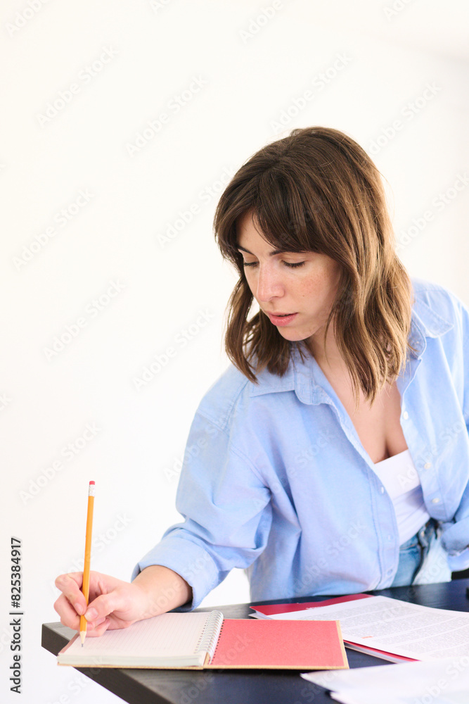 Focused Businesswoman Writing in Notebook at Office Desk Focused Businesswoman Writing in Notebook at Office Desk