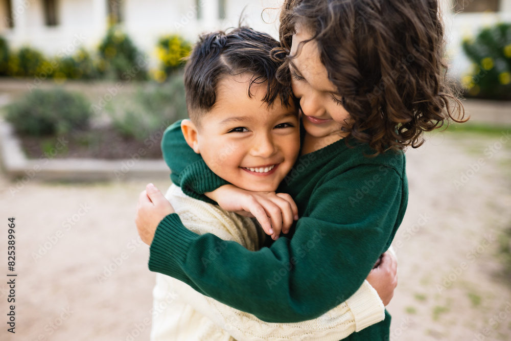 Young brothers joyfully embrace outside while smiling and laughing Young brothers joyfully embrace outside while smiling and laughing