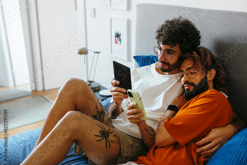 Couple using devices together lying on bed photo