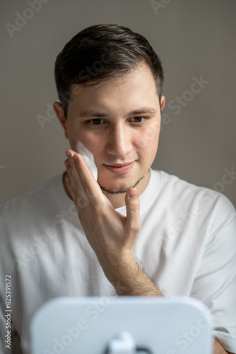 Man applying cleaning foam on his face  photo