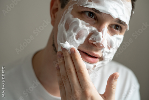 Man applying cleaning foam on his face  photo