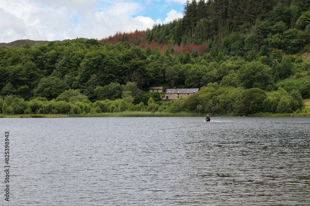 Fototapeta premium Serene lake with rural structures on the shore surrounded by lush greenery
