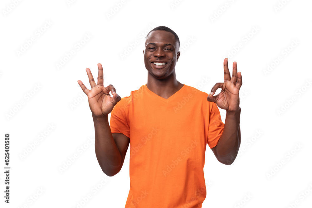 Fototapeta premium young african man dressed in orange t-shirt shows ok gesture and smiles