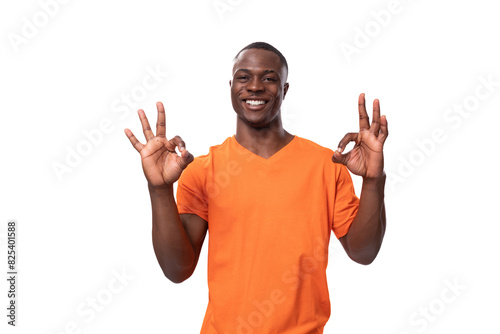 young african man dressed in orange t-shirt shows ok gesture and smiles