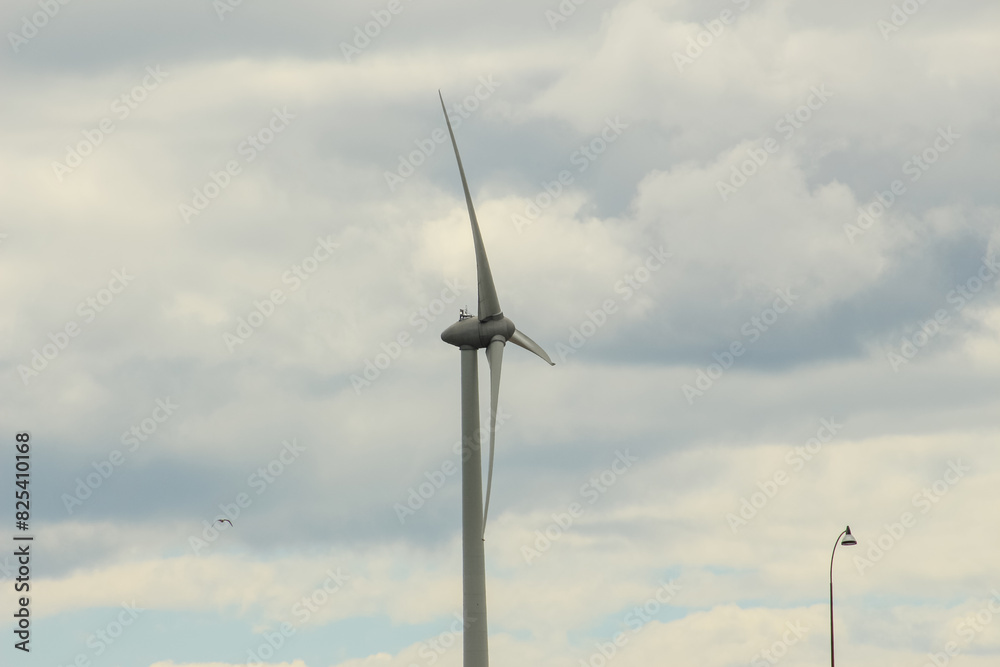 Tall wind turbine generating electricity and lantern against cloudy sky Tall wind turbine generating electricity and lantern against cloudy sky