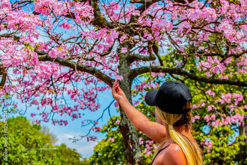 a girl walks through pink guayacan trees