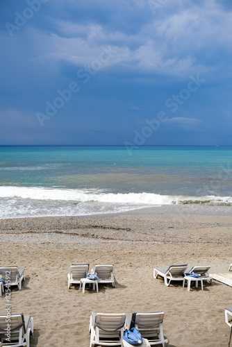 Empty Tourist Beach of Mediterranean Sea with dark blue sky before storm background.