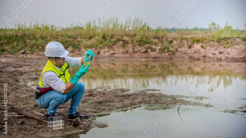 Environmental engineer Sit down next to a well while holding the plastic glass witj both hands support to analysing check the quality and contaminants in the water source. photo