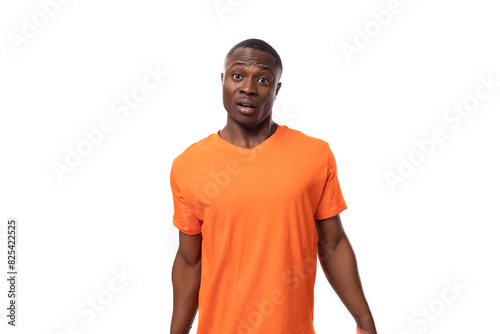 young excited handsome african man dressed in orange t-shirt thinking on studio white background