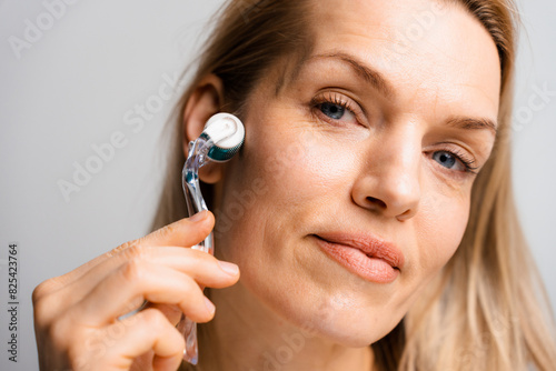 A woman uses a mesoroller for her face photo