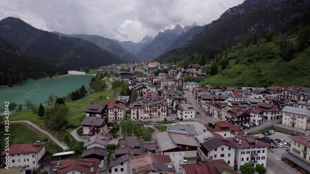 Aerial over beautiful alpine village with a lake and nature on a cloudy day in dolomites, Italy Aerial over beautiful alpine village with a lake and nature on a cloudy day in dolomites, Italy
