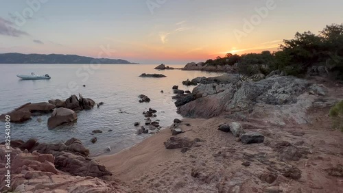 Beautiful view at dawn in a rocky beach and calm sea with a boat in Cala Paradiso, Sardinia photo