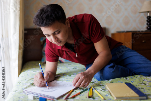 Young man drawing with pencil on a notebook photo