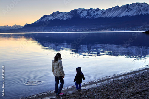 A woman and a child playing by the shore of a lake photo