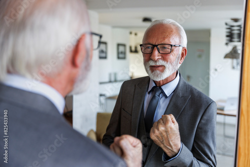 Senior businessman with clenched fist in front of mirror photo