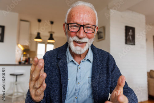 Happy senior businessman gesturing at home photo