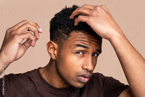 Young man scratching head in confusion photo