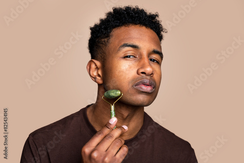 Man using jade roller for skincare routine photo
