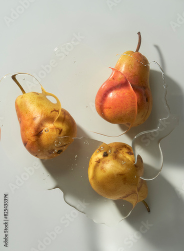 Three glistening pears under glass on a light sunny surface.  photo