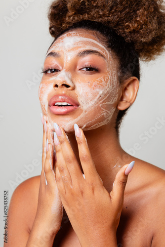 Woman with her hair in a ponytail cleaning her face