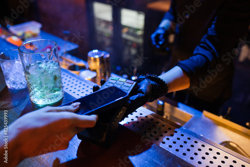 Woman paying for cocktails in the bar by mobile phone  photo