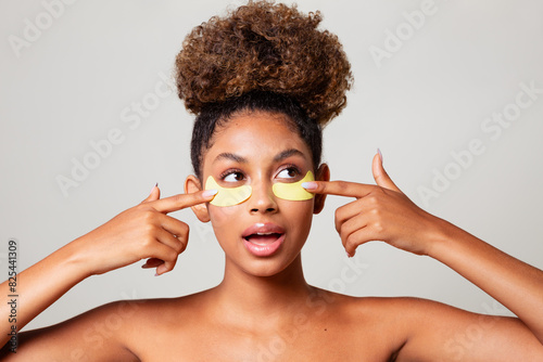 Young woman applying anti-dark circles patches photo