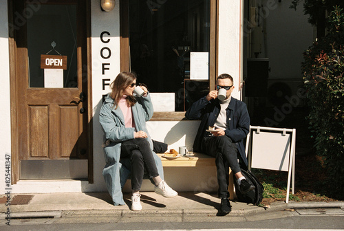 Two friend drinking coffee on a bench photo