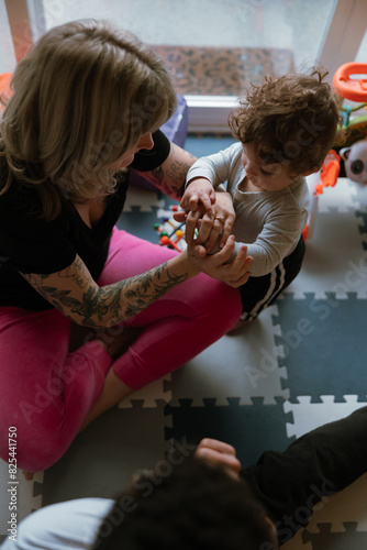 Toddler playing with tattooed adult on floor photo