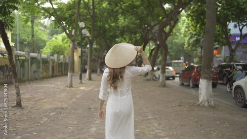 Portrait of Asian Vietnamese woman with Vietnam dress and straw hat in tree corridor in Hanoi. People lifestyle.