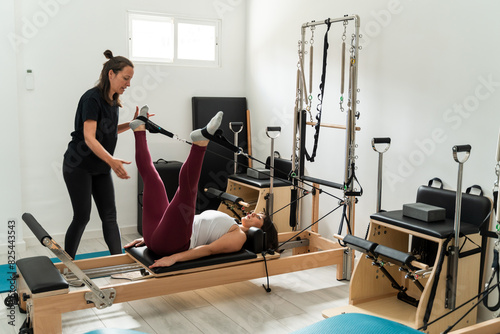 Pilates instructor guiding client on reformer photo