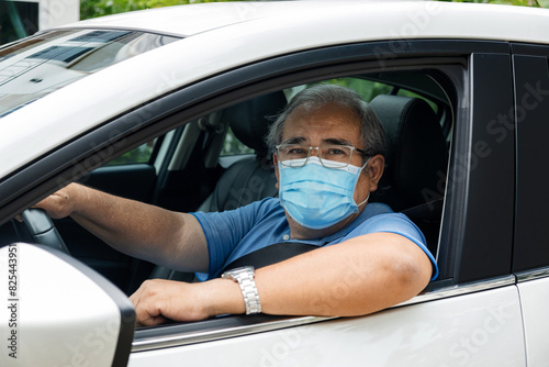 Senior older man driving while wearing a face mask photo