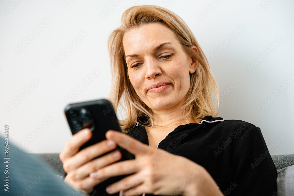 A woman uses a mobile phone sitting in bed A woman uses a mobile phone sitting in bed