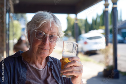 Portrait of older transgender woman sitting outdoors enjoying a beer photo