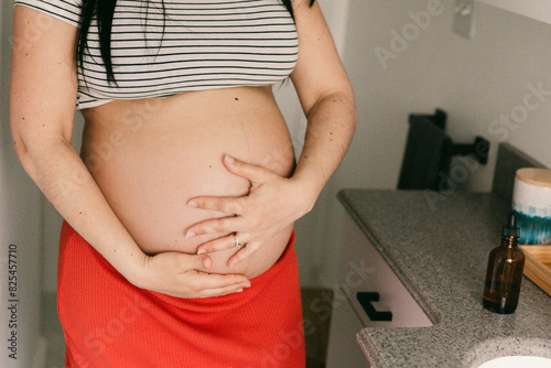 anonymous pregnant woman putting natural oil on her belly photo