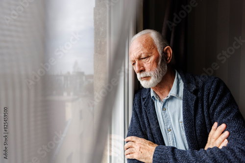 Pensive senior man leaning on window