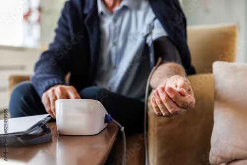 Elderly man checking blood pressure at home photo