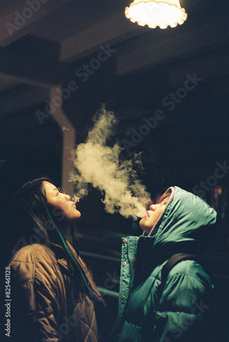 Two women exhaling smoke