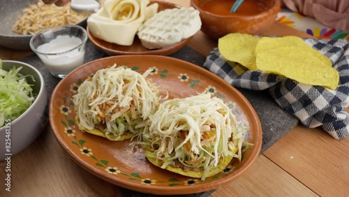 a mexican woman pouring sour cream on mexican tostadas photo