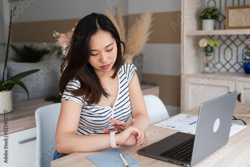 Young woman checking time while working at home photo