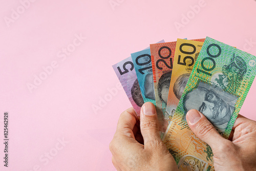 A hand holding Australian money in different dollar values photo