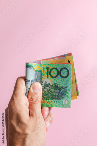 A hand holding several Australian currency dollars bills