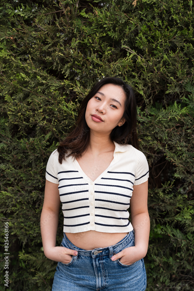 Confident young woman posing in front of greenery Confident young woman posing in front of greenery