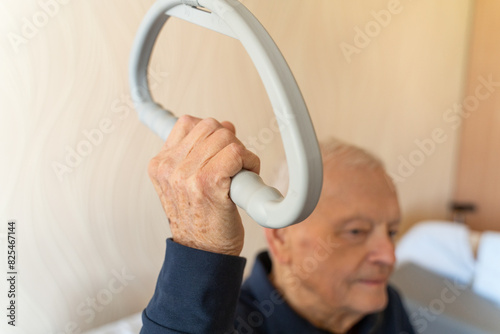 Old Man Holding Trapeze Bar On The Bed photo