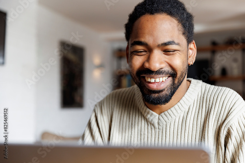 Happy man video calling through laptop photo