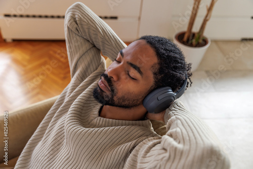 Calm man listening music through headphones at home photo