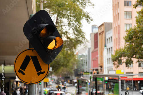 A yellow traffic light with a pedestrian crosswalk sign in Australia