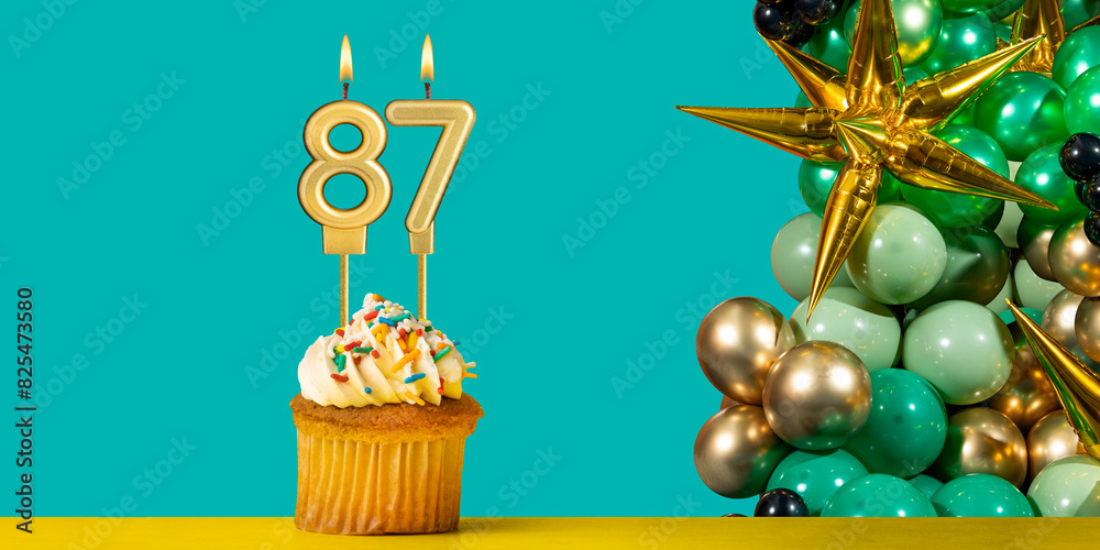 Birthday candle number 87 - Cupcake with decoration on a green background Birthday candle number 87 - Cupcake with decoration on a green background