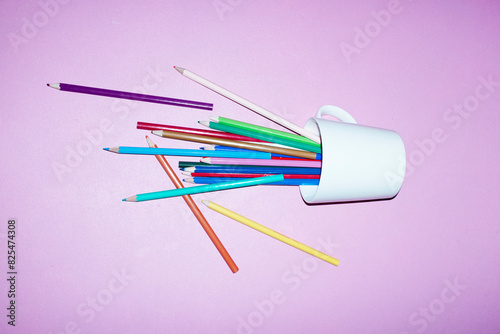 Coffee cup filled with colorful pencils on a office desk with flash photo